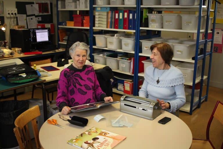 Photo de Marie-Claire et Olga préparant les livres avec texte en braille sur plastique transparent
