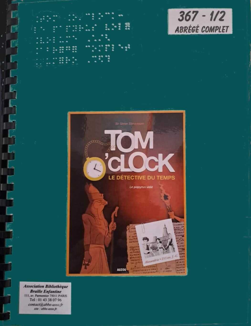 La couverture verte à reliure spirale porte le titre « Tom O'Clock : Le Détective du Temps » et une illustration d'un personnage égyptien antique. On y trouve également du texte en braille et diverses étiquettes de bibliothèque.